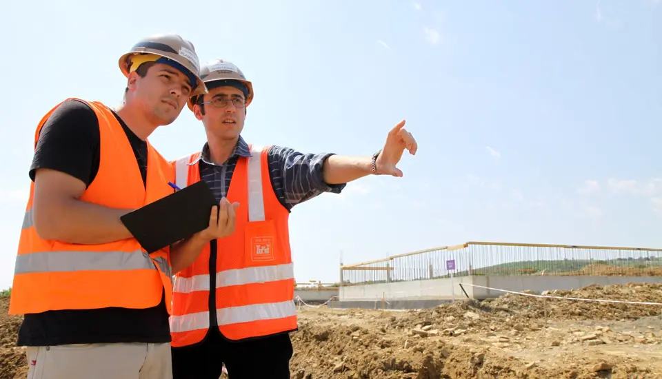 Técnico de campo con casco y chaleco trabajando en exteriores, protegido por un seguro de accidentes
